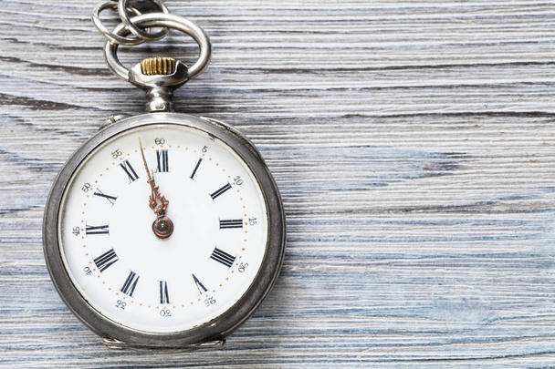 дві хвилини до 12 години на старовинному кишеньковому годиннику на сірому дерев'яному фоні
 - Фото, зображення