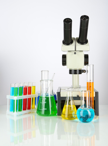 Tubos de ensaio com líquidos coloridos e microscópio isolados a branco
 - Foto, Imagem