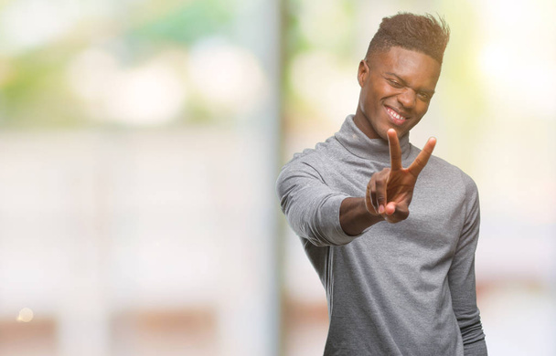 Young african american man over isolated background smiling looking to the camera showing fingers doing victory sign. Number two. - Photo, image