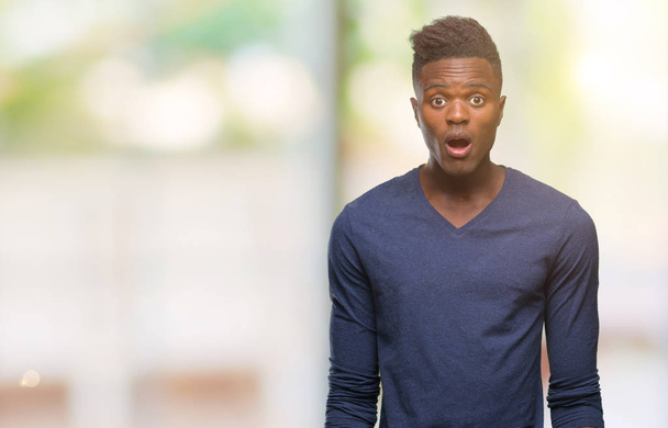 Jonge Afro-Amerikaanse man over geïsoleerde achtergrond bang en geschokt met verrassing expressie, vrees en opgewonden gezicht. - Foto, afbeelding