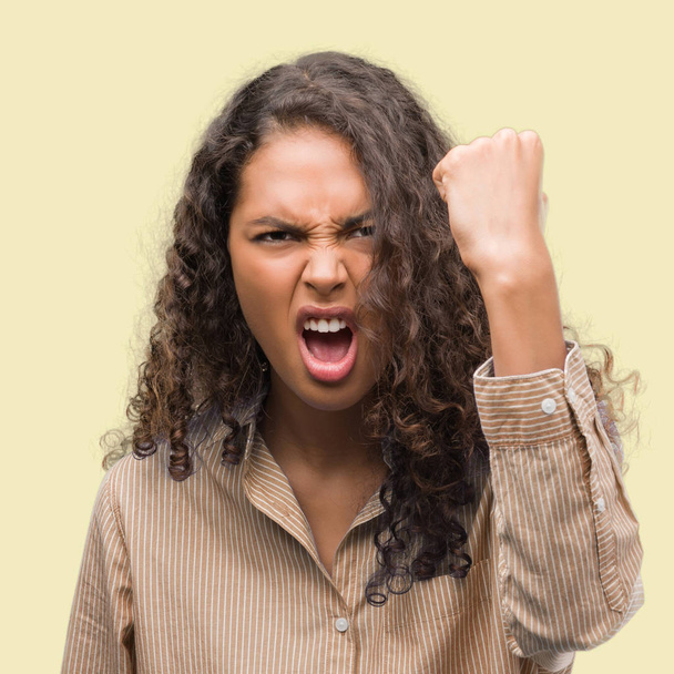 Young hispanic business woman angry and mad raising fist frustrated and furious while shouting with anger. Rage and aggressive concept. - Foto, immagini