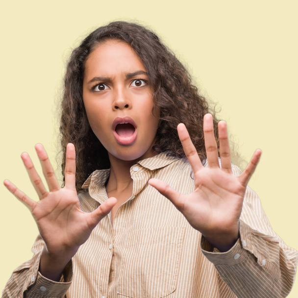 Young hispanic business woman afraid and terrified with fear expression stop gesture with hands, shouting in shock. Panic concept. - Photo, Image