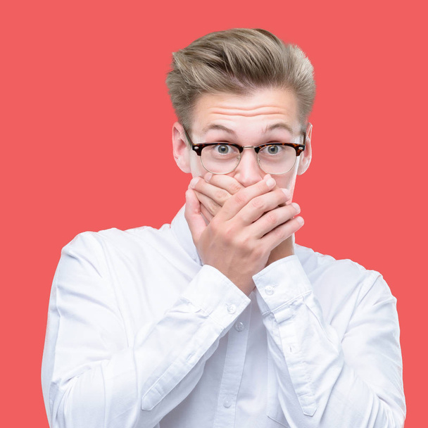 Young handsome blond man shocked covering mouth with hands for mistake. Secret concept. - Foto, afbeelding