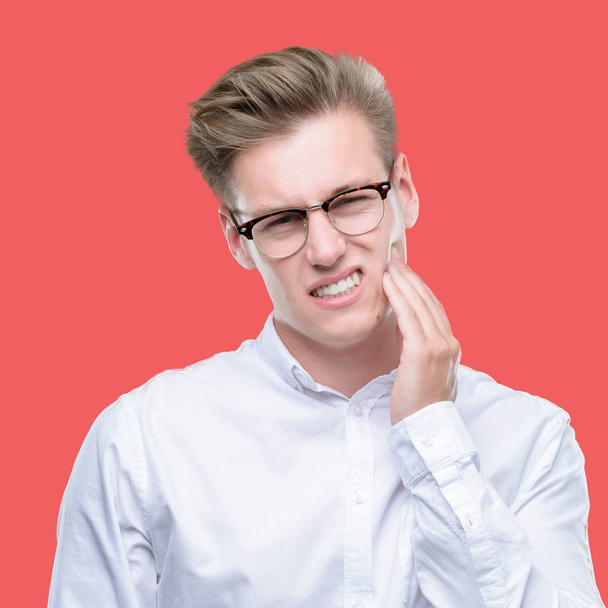 Młody przystojny mężczyzna blond, dotykając usta ręką z bolesne wyrażenie ze względu na ból zęba lub zębów choroby na zęby. Koncepcja dentysta. - Zdjęcie, obraz