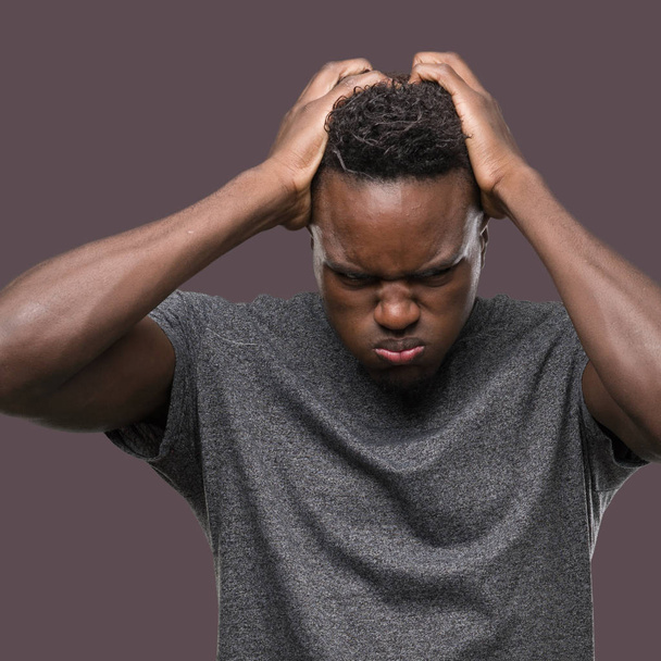 Молодий афроамериканець людиною носіння сіра Маєчка страждають від головного болю, відчайдушні і підкреслив, тому що біль і мігрень. Руки на голову. - Фото, зображення
