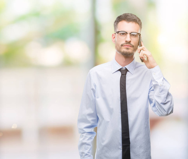Young business adult man talking on the phone with a confident expression on smart face thinking serious - Photo, Image
