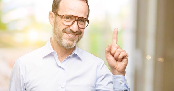 Middle age man with glasses pointing away side with finger - Photo, Image