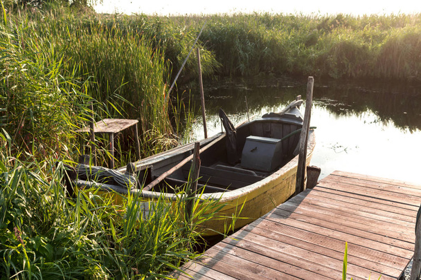 Tôt le matin sur la baie de Vistule. Un bateau de pêche amarré à un petit canot en bois.Roseaux et eau calme. Site sur la nature, mer, pêche, art, fond
. - Photo, image