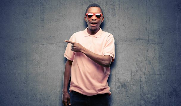 Afrikai fekete ember el oldalán ujjal mutatva napszemüveget visel - Fotó, kép