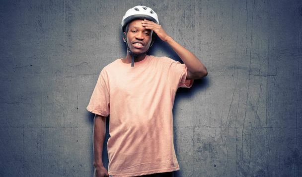 恐怖と不安とパニックのジェスチャー、圧倒を表現する神経系のバイクのヘルメットを身に着けている黒の男 - 写真・画像