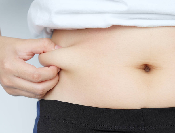 Sivulla nainen käsi kiinni rasvaa vatsa paunch, diabeettinen riskitekijä
 - Valokuva, kuva