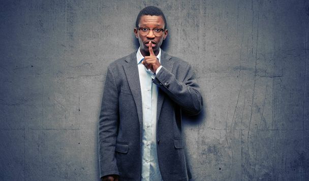 Hombre negro africano con chaqueta con el dedo índice en los labios, pedir silencio. Silencio y concepto secreto
 - Foto, imagen