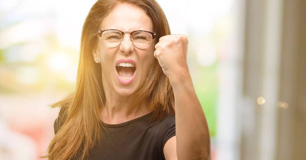 Frau mittleren Alters trägt schwarzes Hemd und Brille irritiert und wütend Ausdruck negativer Emotionen, genervt von jemandem - Foto, Bild