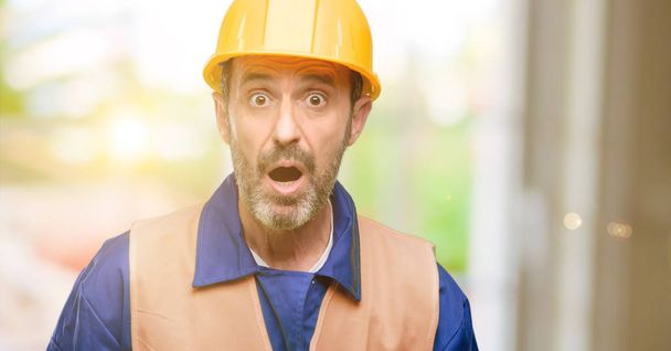Senior engineer man, construction worker scared in shock, expressing panic and fear - Foto, imagen