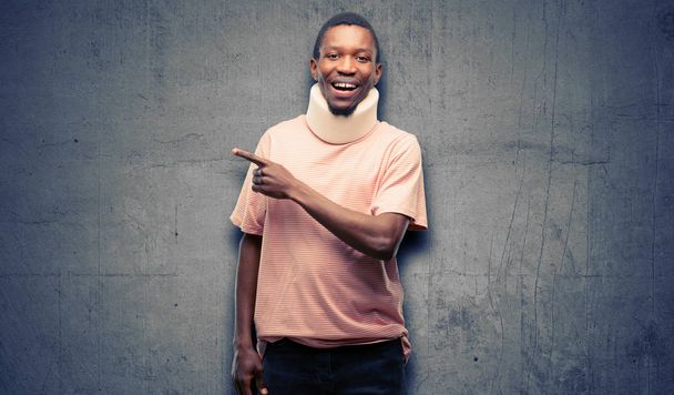 Травмированный афроамериканец в шейном корсете, указывающий пальцем в сторону
 - Фото, изображение