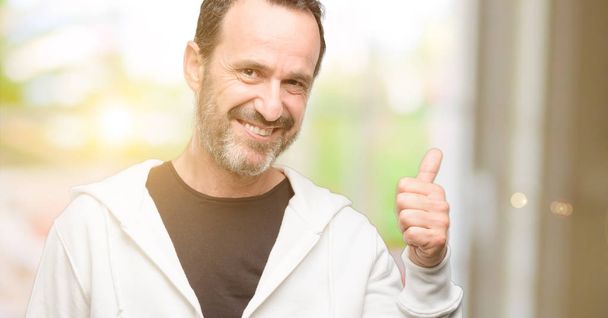 Homme d'âge moyen portant des vêtements de sport souriant montrant largement pouces vers le haut geste à la caméra, expression de similaires et approbation
 - Photo, image