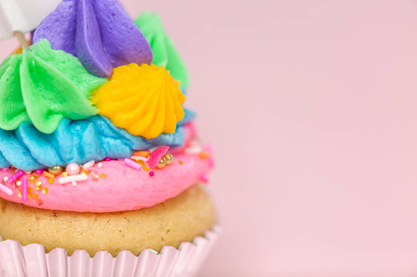 Fancy unicorn cupcakes met multicolor botterroom slagroom en unicorn cupcake topper op roze achtergrond. - Foto, afbeelding