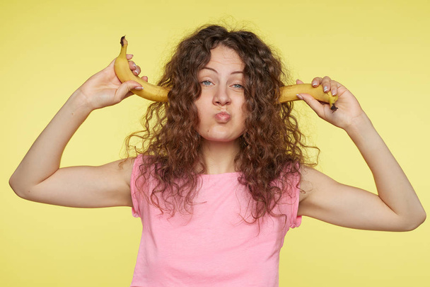 Кумедний постріл кучерявого волосся жінки, що підключає її вуха з бананами, сердитий на своїх сусідів, які дуже галасливі. Роздратована красива молода жінка турист намагається уникнути гучних звуків комах
. - Фото, зображення
