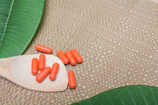 Medicina herbal em cápsulas vermelhas em colher de madeira com espaço de cópia para fundo médico, alimentação saudável com produto natural para uma boa vida
. - Foto, Imagem