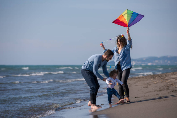 young family with kids resting and having fun with a kite at beach during autumn day - 写真・画像