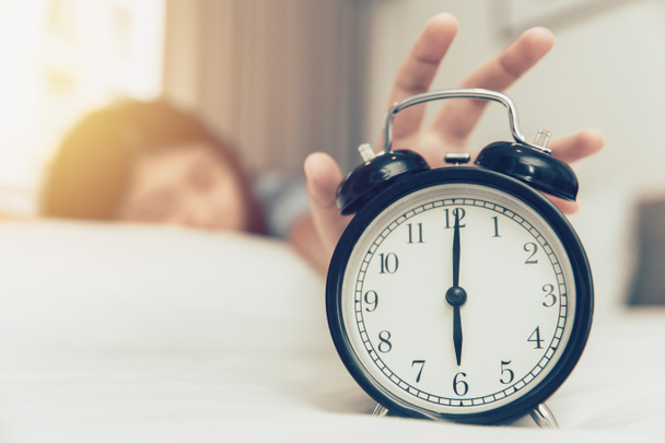 ленивый, чтобы разбудить девушку руку от будильника кольцо на кровати в понедельник утром
 - Фото, изображение