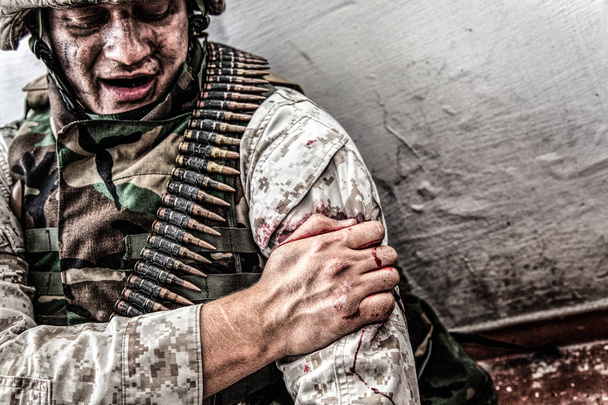 Ranny w ramię żołnierz próbuje zatrzymać krwawienie - Zdjęcie, obraz