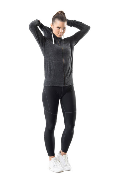 Determined active female jogger put on zip up hoodie sweatshirt looking ahead. Full body length portrait isolated on white background. - Photo, Image