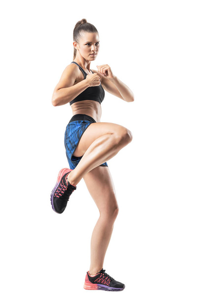 Focused female mma fighter kicking with leg. Stopped action motion. Full body length portrait isolated on white studio background. - Foto, imagen