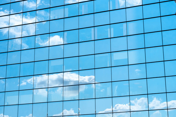 Reflejo del cielo azul y nubes en la pared del espejo del edificio de la ciudad
. - Foto, Imagen