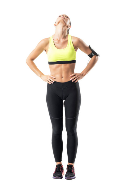 Sportowy kobiece jogger Rozciąganie mięśni szyi z głowy zatytułowany back. Portret długość całego ciała na białym tle. - Zdjęcie, obraz
