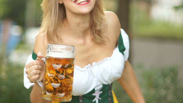 Uma garçonete em um terno nacional bávaro com uma caneca de cerveja alemã em suas mãos faz uma cortesia, arcos e ri alegremente. O festival de cerveja Oktoberfest
 - Filmagem, Vídeo