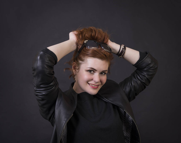 Emotional brunette posing in the Studio in a leather cloak.Isolated image on a dark background. - Φωτογραφία, εικόνα
