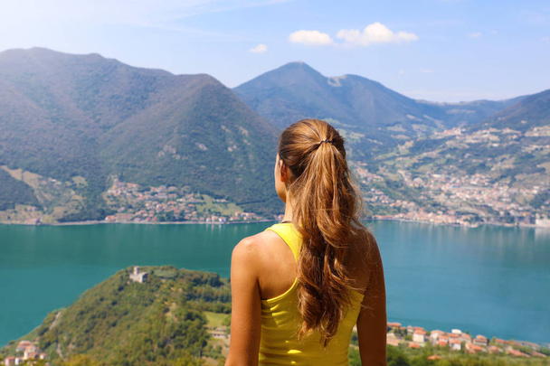 Young woman hiker standing admiring a mountaintop view looking out over distant ranges of mountains and valleys in a healthy active lifestyle concept - Photo, Image