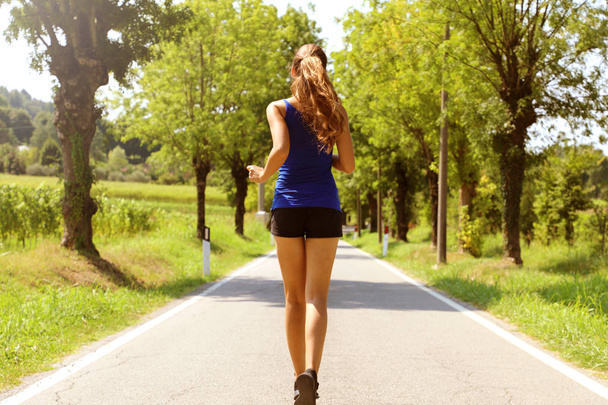 Terveellinen elämäntapa urheilu nainen käynnissä asfaltti ajotieltä. Fitness nainen käynnissä asfalttitiellä
. - Valokuva, kuva