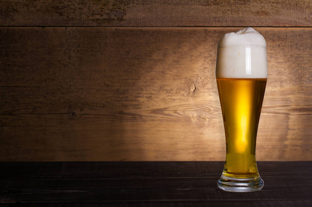 Glass of beer on wooden background with copyspace for text - 写真・画像