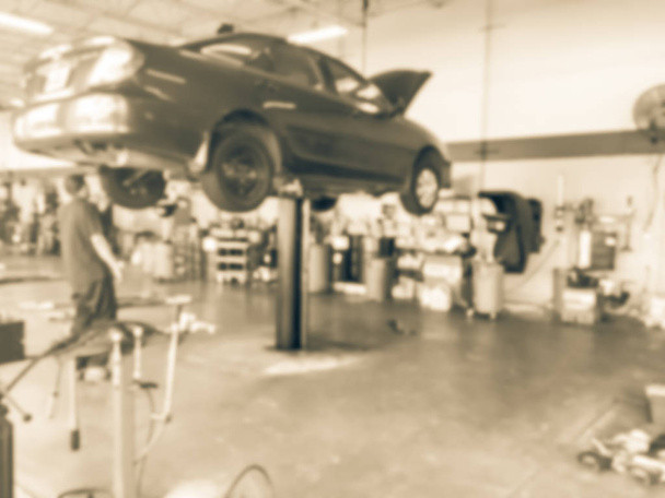 Vintage tón rozmazané abstraktní mechanik zkoumání zvedl auto na auto shop v Texasu, Usa. Pracovní technik v garáži koncept - Fotografie, Obrázek