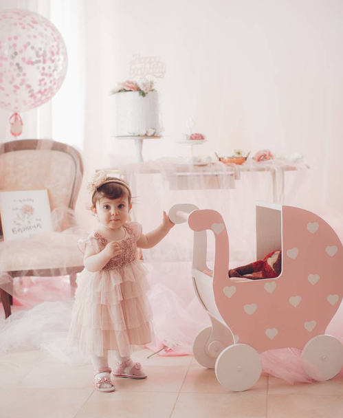 Красива маленька дівчинка в сукні з дитячою каретою святкування дня народження
.  - Фото, зображення