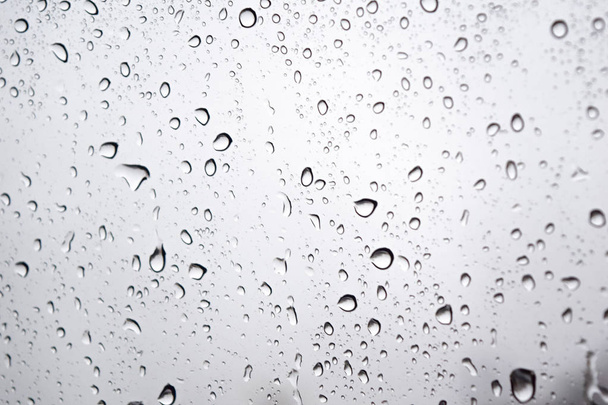 Yağmurlu bir günde cam yüzeyine yağmur damlaları, cama yapışmış su damlacıkları, yalnız renk tonu. - Fotoğraf, Görsel