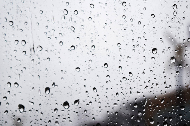 Раинкапельки на стеклянной поверхности в дождливый день, Вода даёт прикрепиться к стеклу, одинокий цветовой тон - Фото, изображение