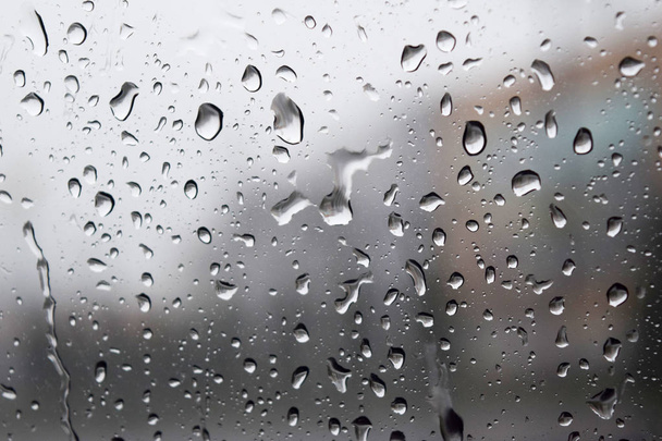 Las caídas de lluvia en la superficie de vidrio en días lluviosos, Las gotas de agua adjuntas en el vidrio, tono de color solitario. - Foto, Imagen