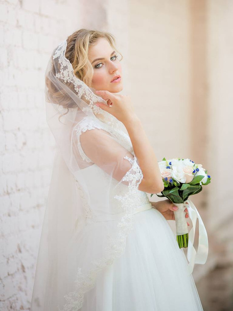 Όμορφη νεαρή νύφη άσπρο γαμήλιο φόρεμα ποζάρουν  - Φωτογραφία, εικόνα