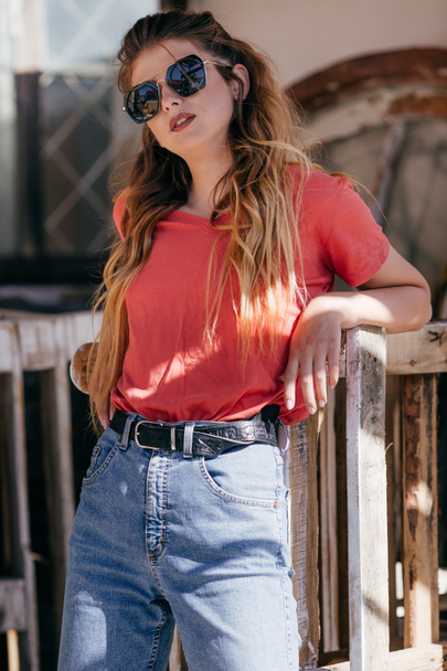 Hermosa mujer joven en jeans y camiseta roja posando en el estudio
  - Foto, Imagen