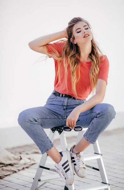 Krásná mladá žena v džínách a červené tričko pózuje ve studiu  - Fotografie, Obrázek
