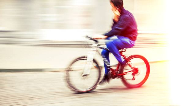 Abstract blurred image of cyclist on the city roadway. Intentional motion blur and color shift - Photo, Image
