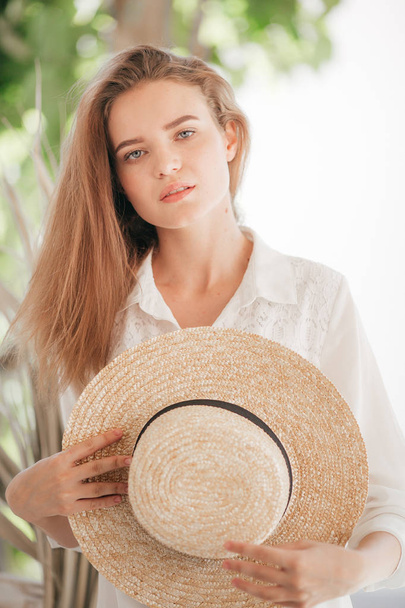 Όμορφη νεαρή γυναίκα που ποζάρει στο καλοκαίρι με ψάθινο καπέλο - Φωτογραφία, εικόνα