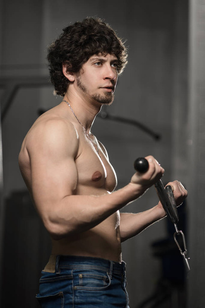 Athletic muscular man training biceps in the gym - Photo, image