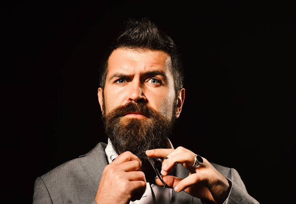 Man with beard holds steel scissors. Businessman with calm face - Foto, Bild