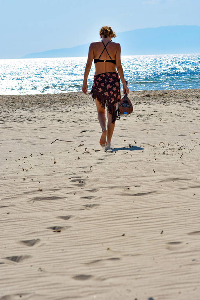 woman holding a mandolin while walking at the beach - Foto, imagen