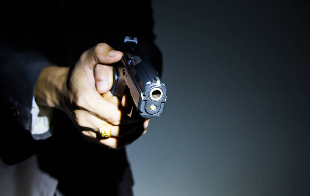 暗い背景のテキスト表示用の銃を持っている男性の手を閉じる - 写真・画像