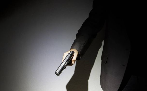 暗い背景のテキスト表示用の銃を持っている男性の手を閉じる - 写真・画像